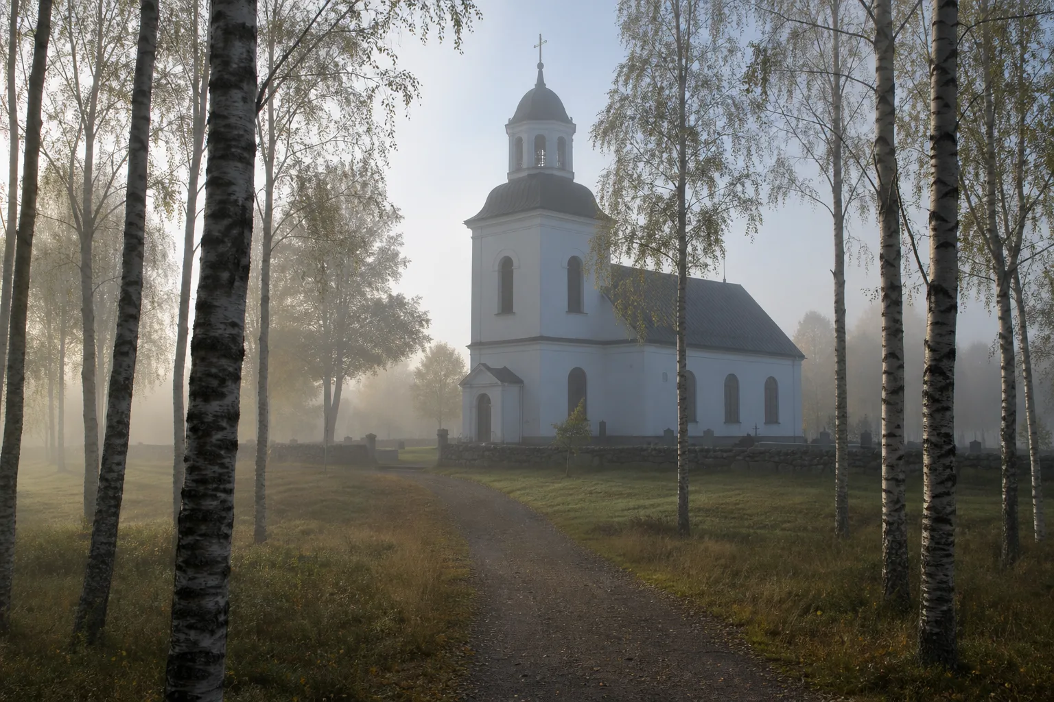 Svensk landsbygdskyrka omgiven av björkar i morgondimma